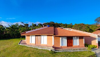 Una casa de un piso con techo de tejas, paredes de ladrillo y un pequeño porche.