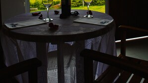 Una mesa con una botella y dos copas de vino, frente a una vista panorámica de colinas y un cielo despejado.