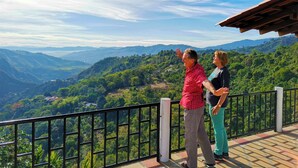 Dos personas en un balcón con vistas a un paisaje montañoso.