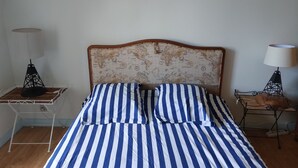 A bed with a world map headboard, striped bedding, and two bedside lamps. - Charmante Maison de Village , Tout à Pied, Commerces et Plage à 5 mn (Perros-Guirec)