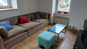A cozy living room with a sofa, a small table, and a television. - Charmante Maison de Village , Tout à Pied, Commerces et Plage à 5 mn (Perros-Guirec)