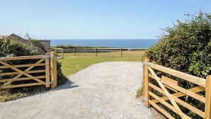 A gravel path leading to a wooden gate with a view of the sea. - Lundy View Chalet (Bude)