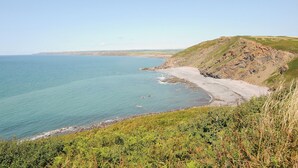 A coastal landscape with a beach, rocky cliffs, and a clear sky. - Lundy View Chalet (Bude)