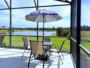 A covered patio with a table and chairs, overlooking a lake. - Cozy Family Friendly Pool Home With Game Room-227y 5 Bedroom Home by RedAwning (Davenport)