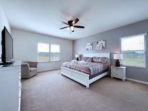 A bedroom with a bed, a ceiling fan, a TV, a chair, and a dresser. - Cozy Family Friendly Pool Home With Game Room-227y 5 Bedroom Home by RedAwning (Davenport)