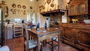 A rustic kitchen with wooden furniture, a brick wall, and various kitchen utensils hanging on the wall. - Monticchiello (Pienza)