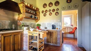 A kitchen with wooden cabinets, a brick wall, and a tiled backsplash. - Monticchiello (Pienza)