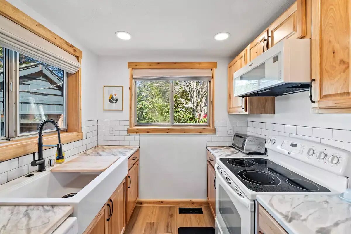 A compact kitchen with a sink, stove, and wooden cabinets.
