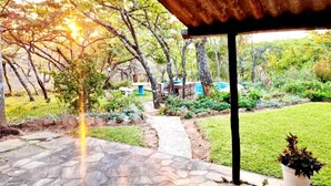 Un patio couvert doté d’un sol en pierre, entouré d’une végétation luxuriante et d’arbres.
