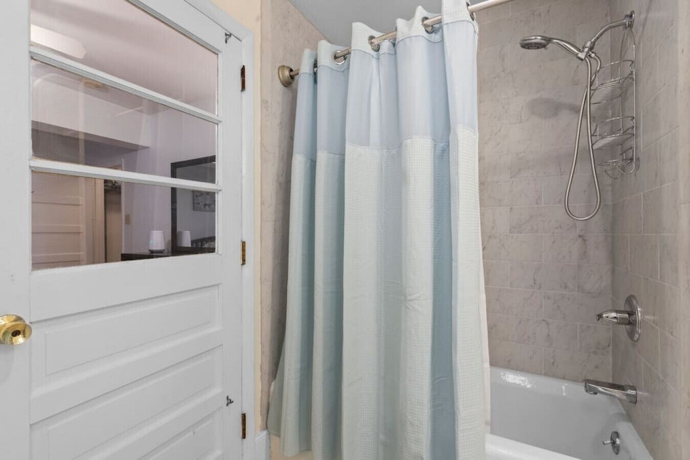 Un baño con ducha, bañera y una puerta blanca con panel de vidrio.