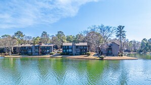 Un quartier résidentiel au bord d’un lac, avec des immeubles à plusieurs étages, une jetée et un ciel dégagé.