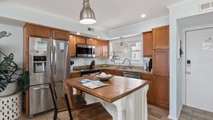 A modern kitchen with wooden cabinets, stainless steel appliances, and a central island. - Canal-Front Townhome w/ Private Boat Slip, Pool & Beach Access (Carolina Beach)