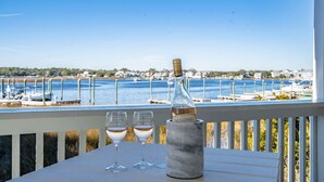 A balcony with a view of a marina, a bottle of wine, and two glasses on a table. - Canal-Front Townhome w/ Private Boat Slip, Pool & Beach Access (Carolina Beach)