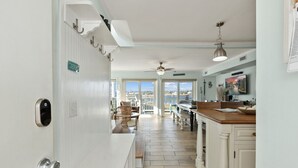 A spacious kitchen with a view to the outside, a dining area with a table and chairs, and a ceiling fan. - Canal-Front Townhome w/ Private Boat Slip, Pool & Beach Access (Carolina Beach)