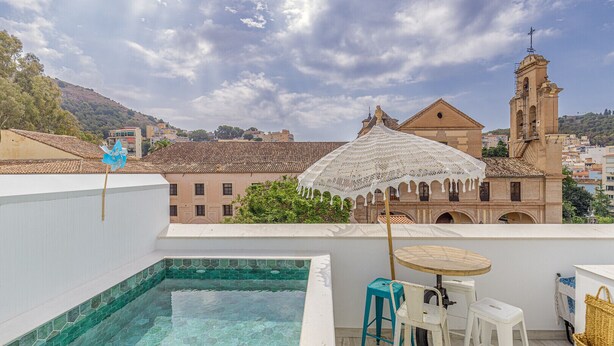 A rooftop pool area with a view of a historic building and a bell tower. - Petite Maison Lili (Málaga)