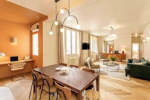 Ein modernes Wohnzimmer mit einem Holzesstisch, Stühlen, einer Couch und einem Fernseher.