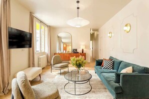 A modern living room with a sofa, armchair, coffee table, and a TV. - Grand apartment in the Art Deco building - 3 bedrooms - A/C - Sentier district - Feydeau by Habitat Parisien (Paris)