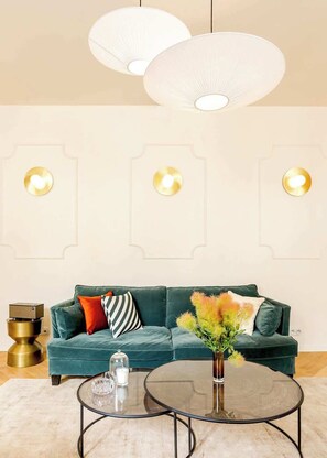 Una sala de estar moderna con un sofá azul aguamarina, una mesa de centro de vidrio y lámparas colgantes.