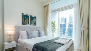 Un dormitorio moderno con una cama grande, una mesita de noche con lámpara y dos cuadros enmarcados en la pared.