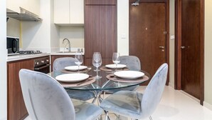 Una cocina moderna con una mesa de comedor dispuesta para cuatro personas, equipada con sillas de cristal y una superficie de vidrio.