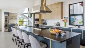 A modern kitchen with a large island, bar stools, and a built-in stove. - Staffed Luxury Oceanview Villa w/ golfcart, jacuzzi, infinity pool &breakfast (Playa Tamarindo)