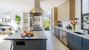 A modern kitchen with a central island, stainless steel appliances, and wooden cabinetry. - Staffed Luxury Oceanview Villa w/ golfcart, jacuzzi, infinity pool &breakfast (Playa Tamarindo)