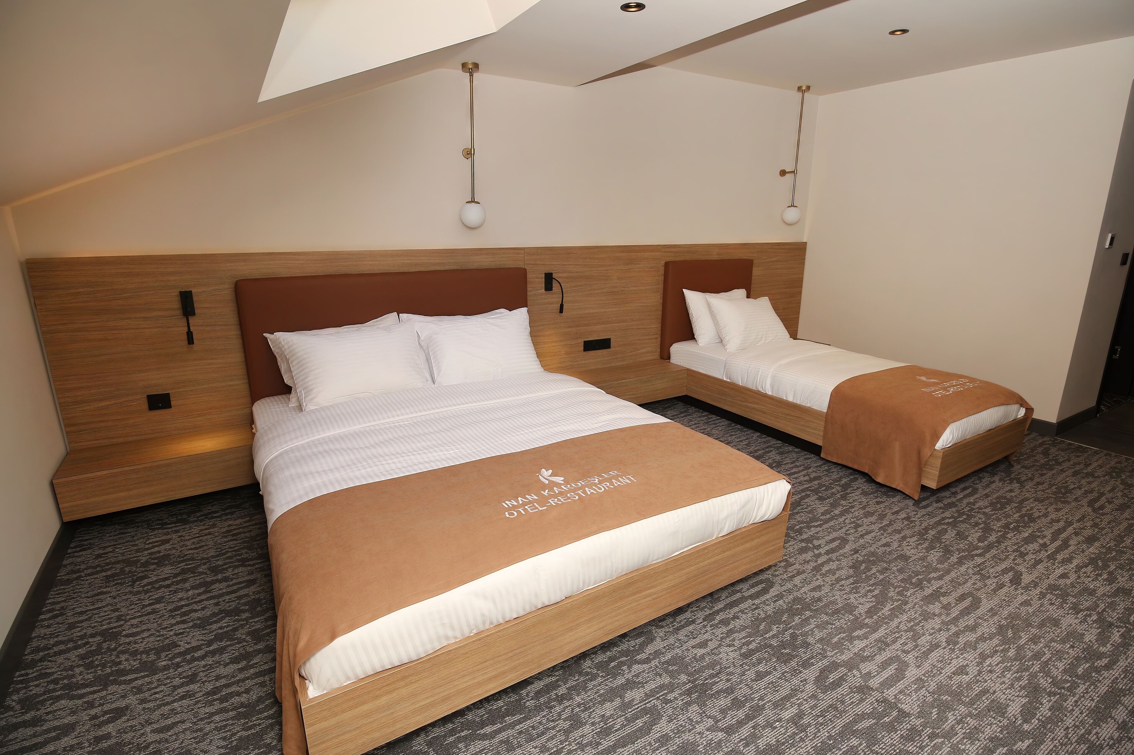 A hotel room with two beds, a wooden headboard, and a carpeted floor.