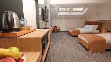 Quarto de hotel com cozinha compacta, duas camas, televisão e claraboia.
