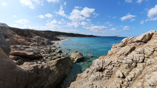 A rocky coastline with clear blue waters and a white van parked on the beach. - Case Vacanza Rena Majore (Aglientu)