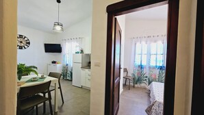 A compact living space with a dining area, kitchenette, and a bedroom. - Case Vacanza Rena Majore (Aglientu)