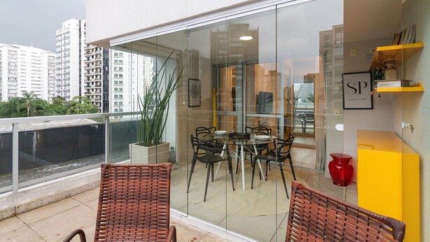 A balcony with wicker chairs, a glass table, and a yellow cabinet. - Wish Moema 15 (São Paulo)