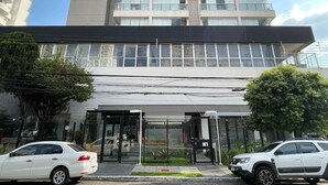A modern building with a glass entrance and two white cars parked in front. - Wish Moema 15 (São Paulo)