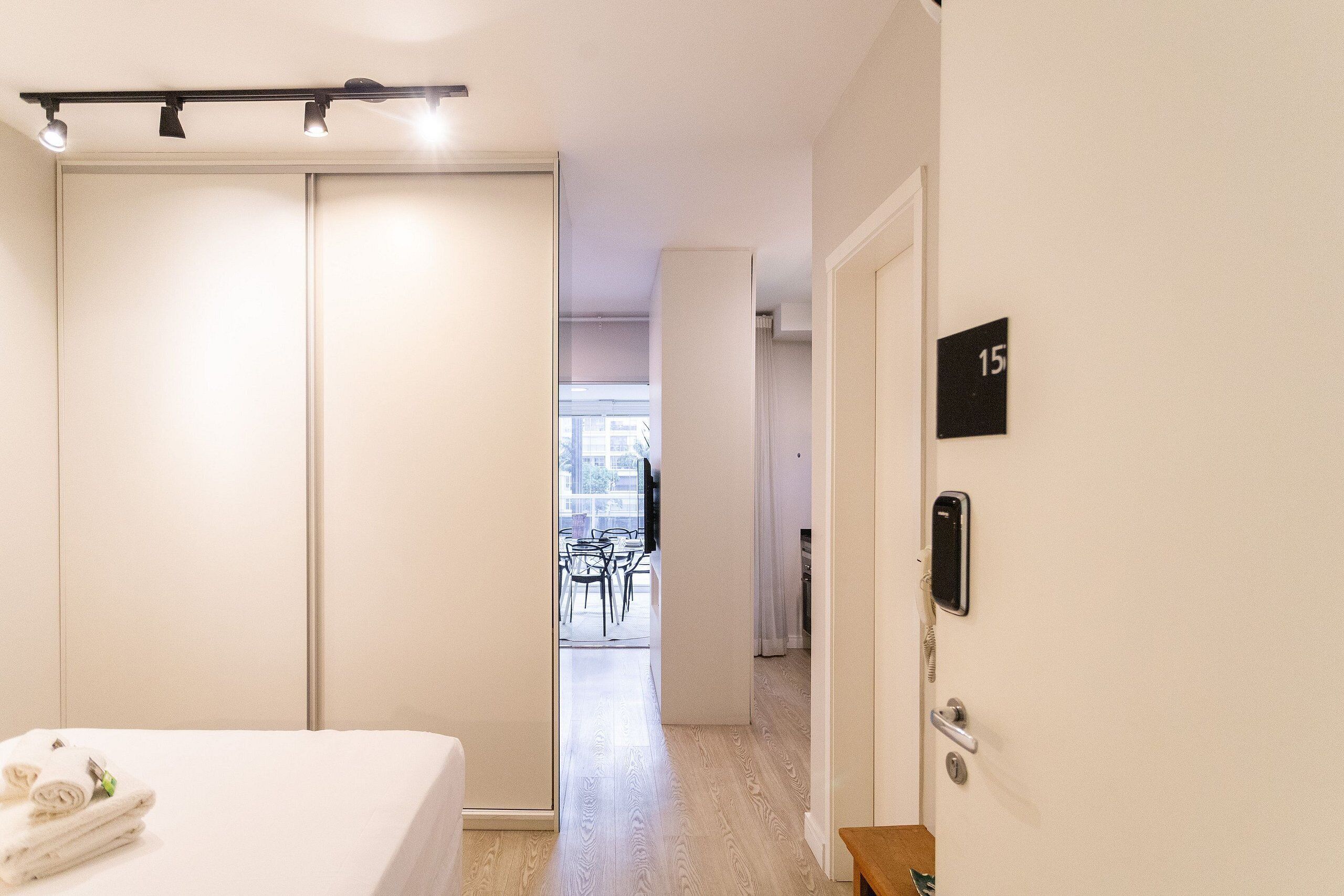 Ein Hotelzimmer mit einem Bett, einem Kleiderschrank, einer Tür mit Telefon und Blick auf den Speisesaal.