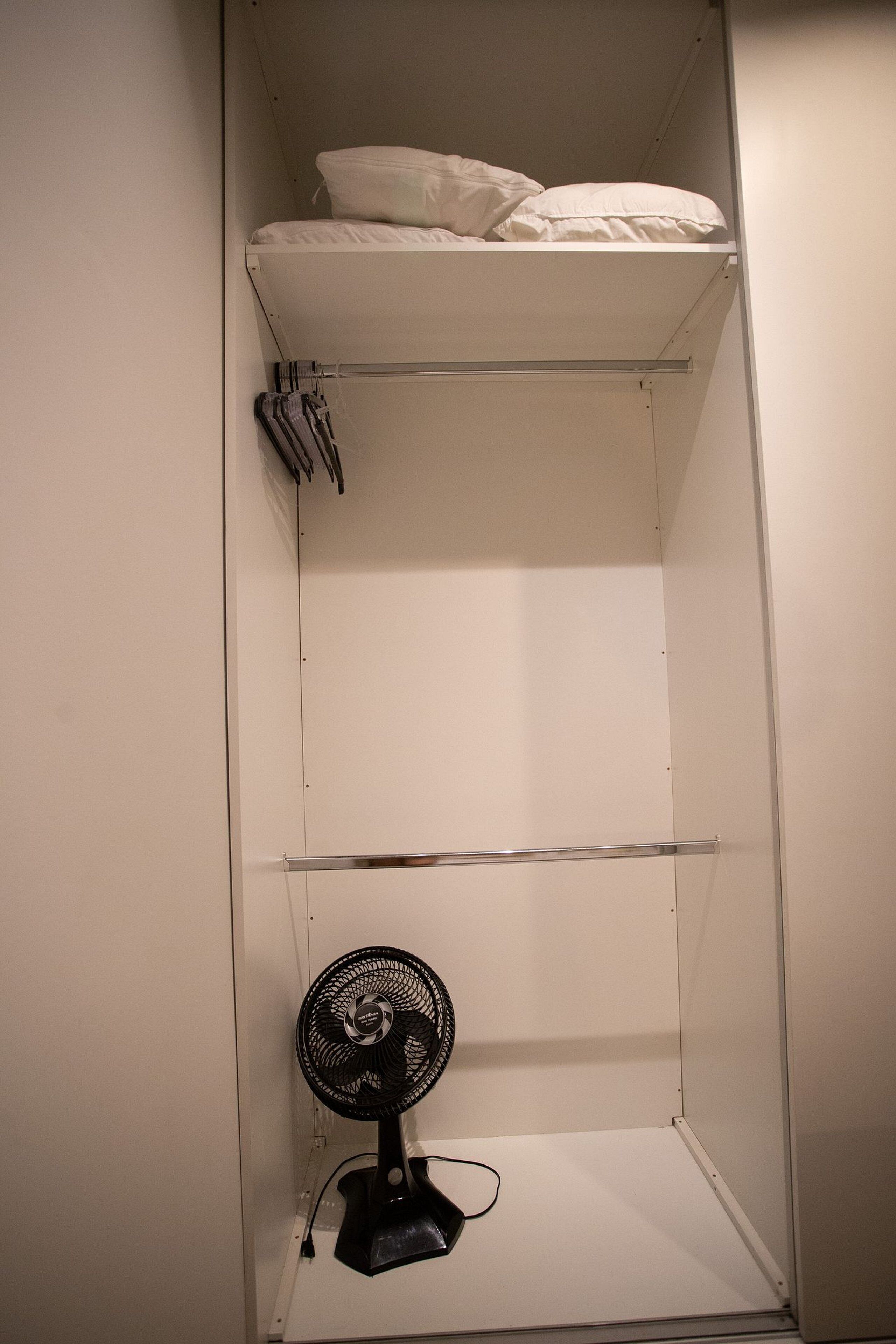 A bunk bed with a fan and a shelf above it.