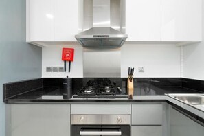 Eine moderne Küche mit Gasherd, Edelstahlunterschränken und einem roten Schild an der Wand.
