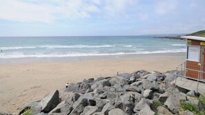 Una spiaggia con una postazione di salvataggio e affioramenti rocciosi.