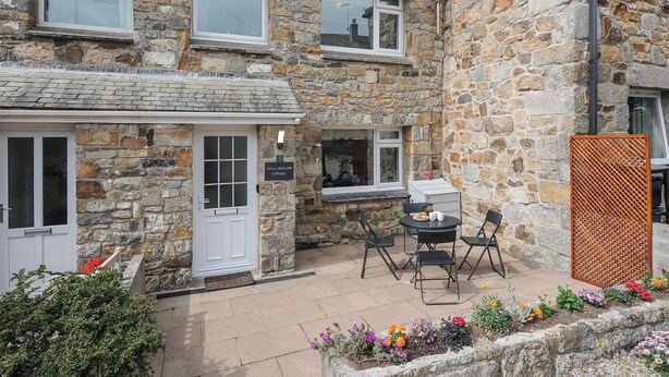 Un cottage in pietra con patio, tavolo e sedie.