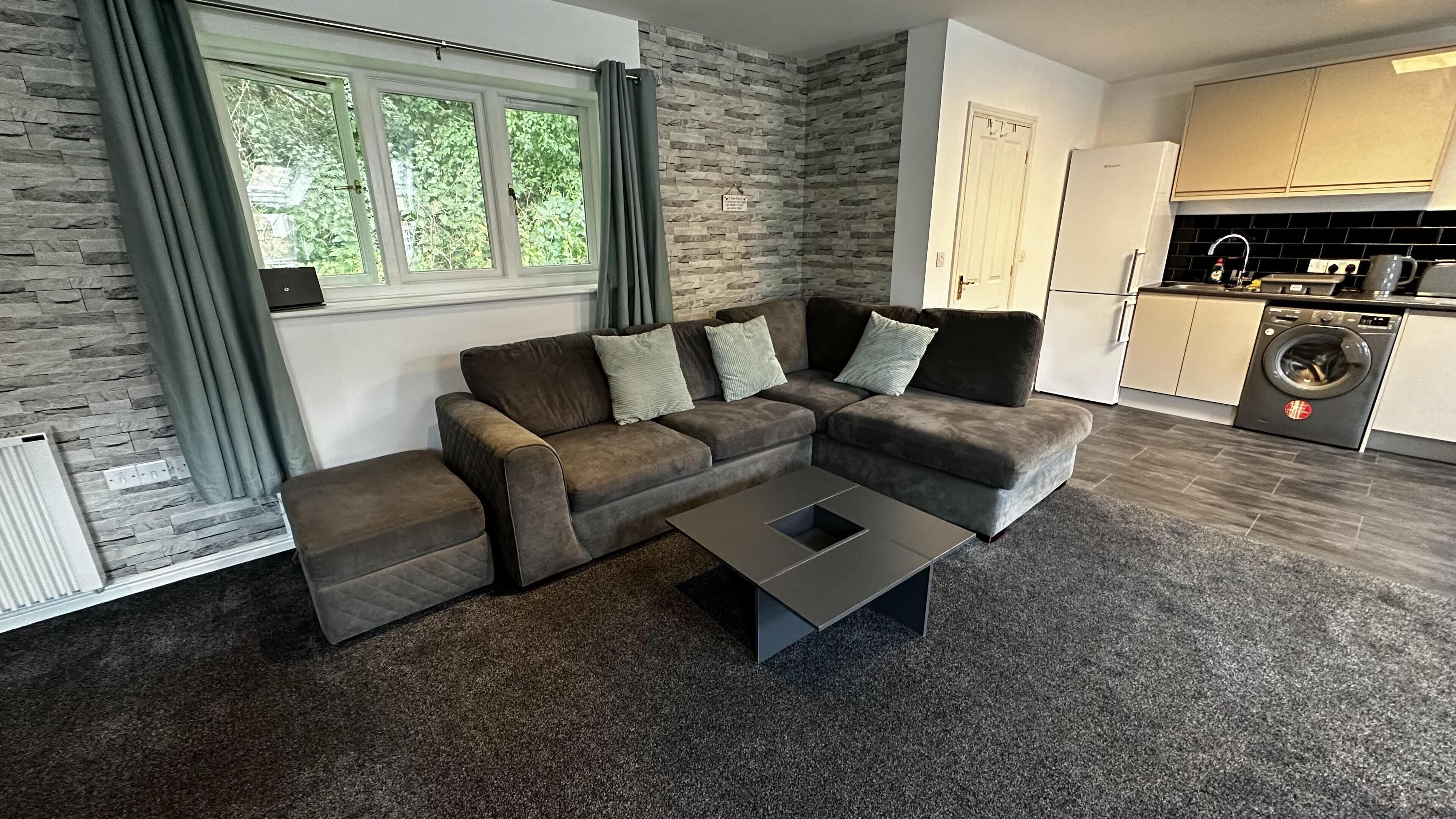 Een moderne woonkamer met een modulaire bank, een salontafel en uitzicht op de keuken.
