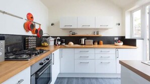 Una cocina moderna con armarios blancos, encimera de madera y cocina a gas.