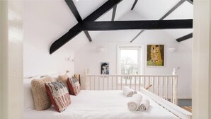 Un dormitorio con una cama blanca, barandillas blancas y un cuadro en la pared.