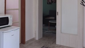 Een hal met een witte magnetron op een klein wit apparaat, een witte deur en een kamerbreed tapijt met patroon op de vloer.