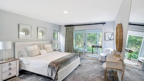 A bedroom with a large bed, a desk, and a view of the outdoors. - Contemporary home close to beaches with private pool, open floorplan, and... (East Quogue)