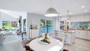 A modern kitchen with white cabinetry, a central island, and pendant lighting. - Contemporary home close to beaches with private pool, open floorplan, and... (East Quogue)
