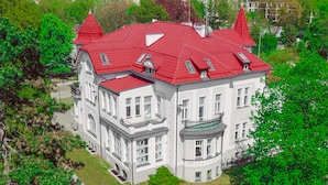 A large, white building with red roofs and multiple windows, surrounded by greenery. - Srebrna Luxury Apartments (Lodz)