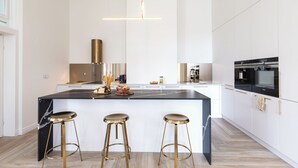A modern kitchen with a large island, bar stools, and stainless steel appliances. - Srebrna Luxury Apartments (Lodz)