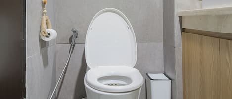 Un baño moderno con inodoro blanco, ducha y lavamanos.