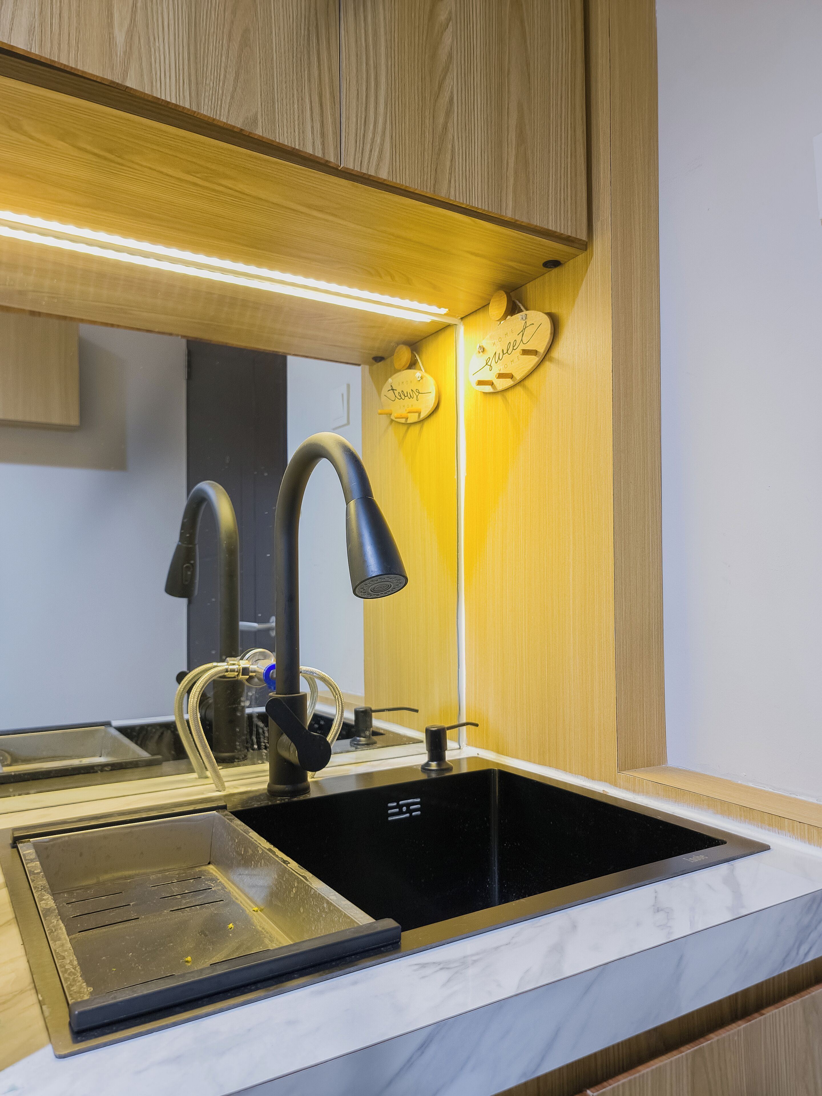 A modern kitchen with a black faucet, a stainless steel sink, and wooden cabinetry.