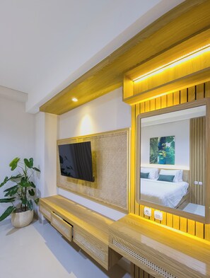 Un dormitorio moderno con un espejo grande, un televisor de pantalla plana y un banco de madera.