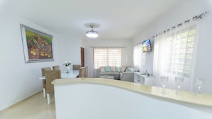 A modern living room with a curved white counter, a sofa, a television, and a painting on the wall. - Puerto Plata (Puerto Plata)
