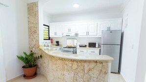 A kitchen with white cabinets, a granite countertop, a stainless steel refrigerator, and a gas stove. - Puerto Plata (Puerto Plata)